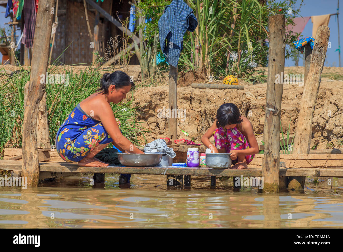 Mère et fille à laver les vêtements en face de leur maison, au Lac Inle au Myanmar Banque D'Images