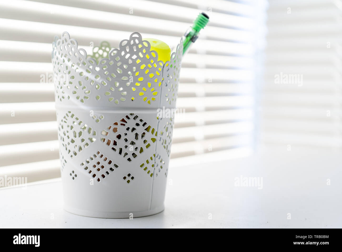 Récipient décoratif utilisé comme un porte-crayons dans un bureau à domicile, contre une fenêtre, avec rayons et blanc décor à la maison. Banque D'Images