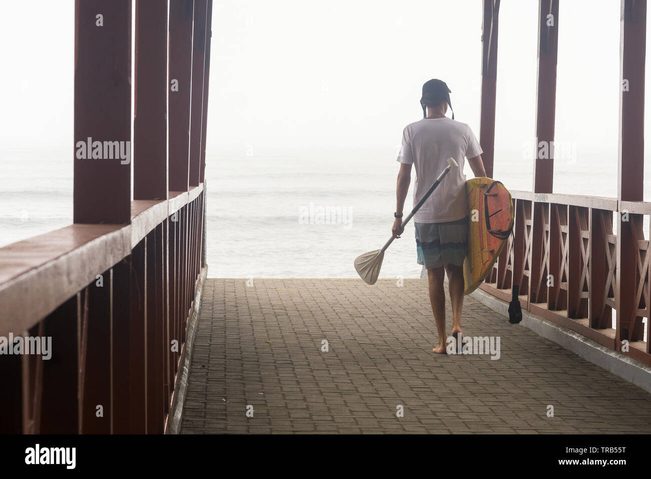 Homme marchant avec paddle board vers la plage dans Barranco, Lima, Pérou. Banque D'Images