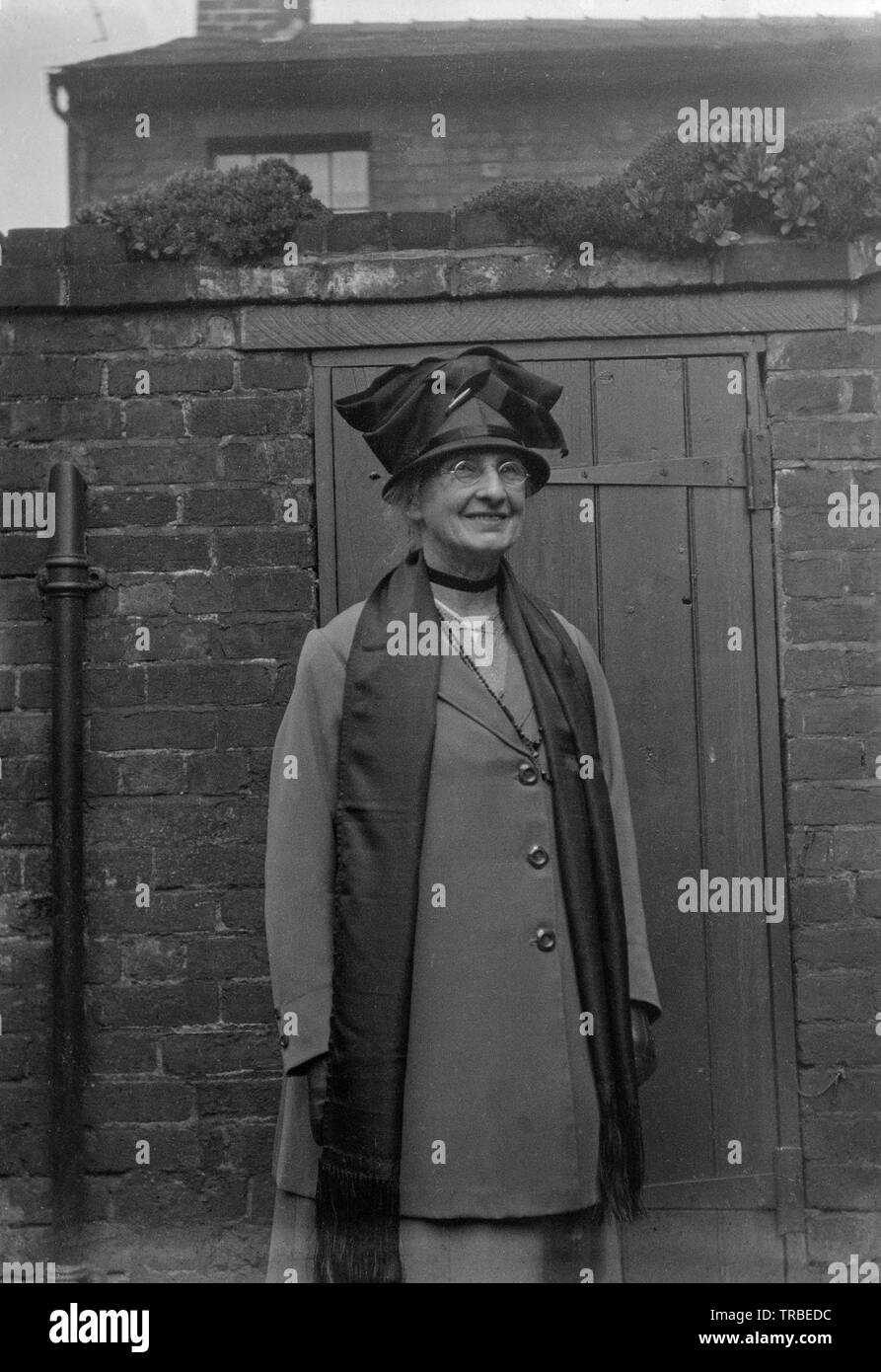 Un début du xxe siècle vintage noir et blanc photographie d'une femme d'âge moyen, vêtu de son mieux les vêtements et chapeau. Photographie prise à l'extérieur de l'arrière d'une propriété en Angleterre. Banque D'Images