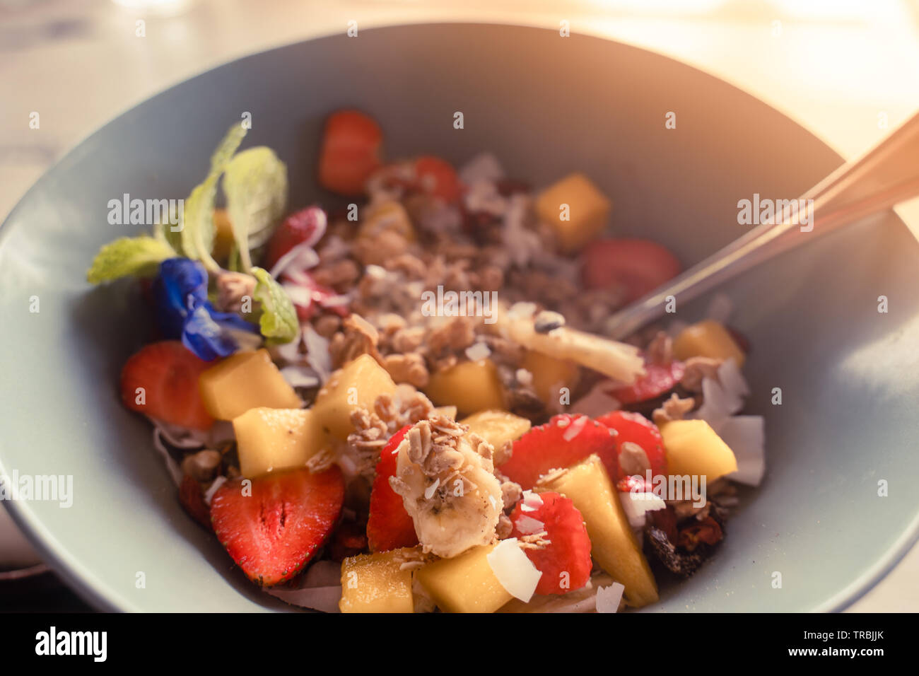 Petit-déjeuner sain porridge concept : avoine avec flocons de noix de coco, fraise, banane et mangue morceaux servis avec du yaourt grec et de miel naturel Banque D'Images