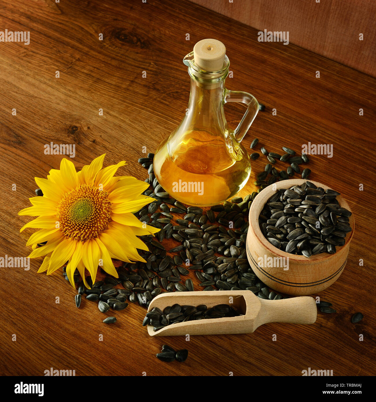 L'huile de tournesol, graines et fleurs sur un fond de bois Banque D'Images
