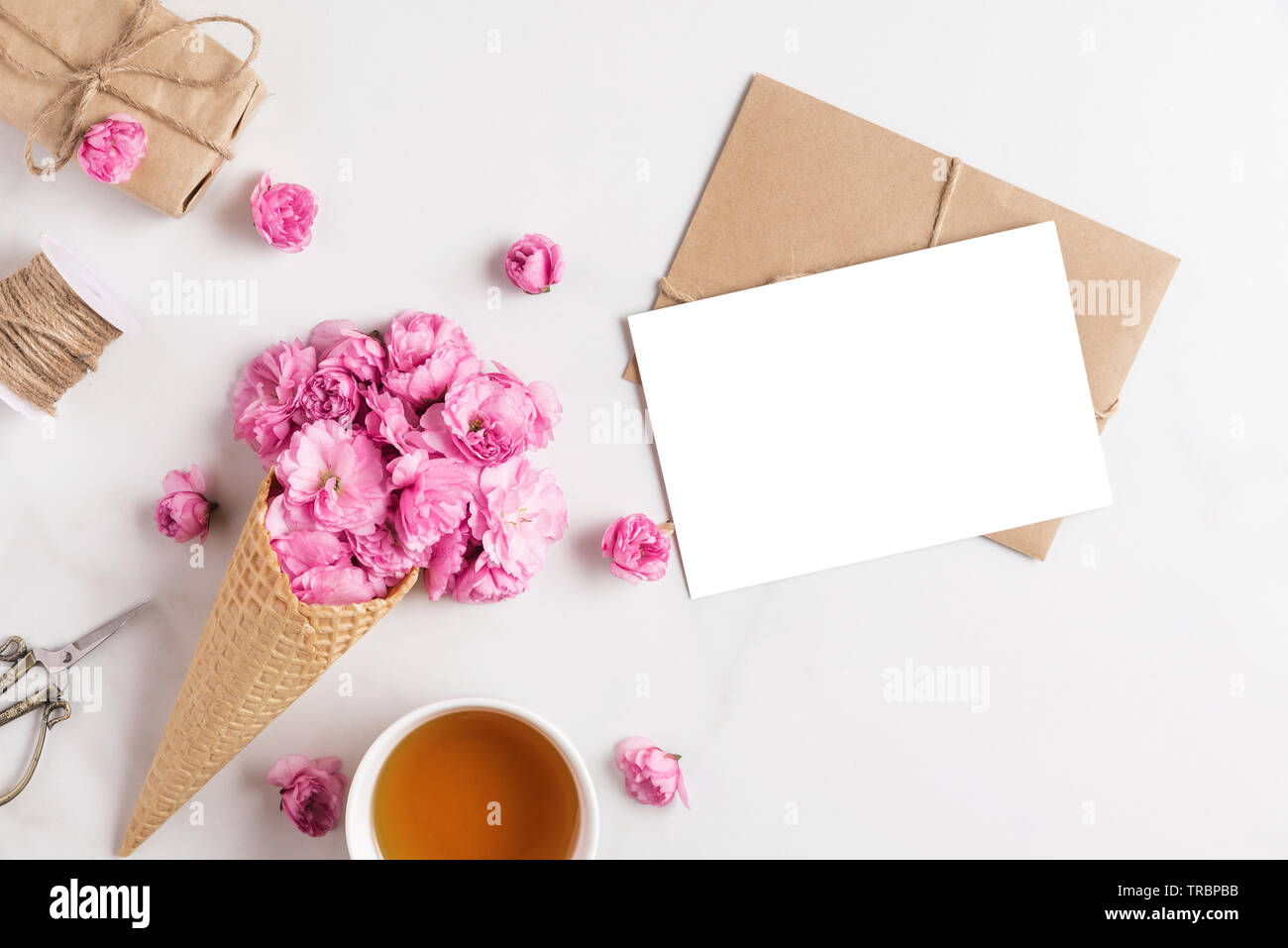 Carte de vœux en blanc et rose des fleurs de cerisier en fleurs en cornet gaufré sur fond de marbre blanc avec une tasse de thé et boîte-cadeau. télévision lay Banque D'Images