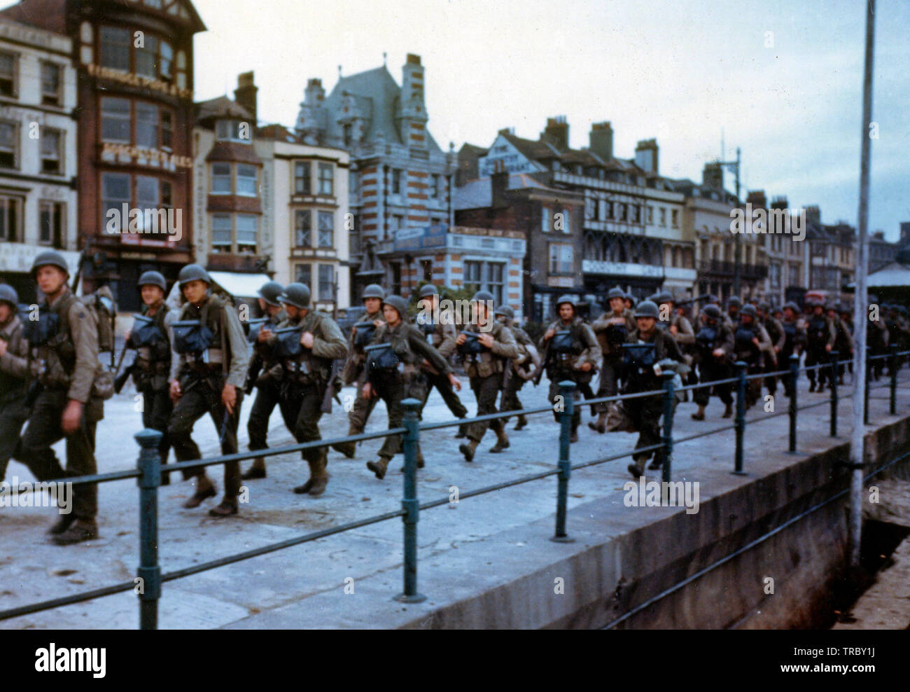 Ces troupes américaines marchons à travers les rues d'une ville portuaire britannique en route pour les docks où ils seront déposés dans des engins de débarquement pour le grand assaut. Juin, 1944 Banque D'Images