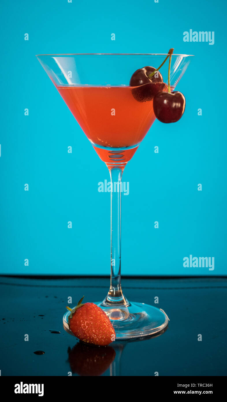 Un cocktail rouge dans un grand verre avec fond bleu Banque D'Images