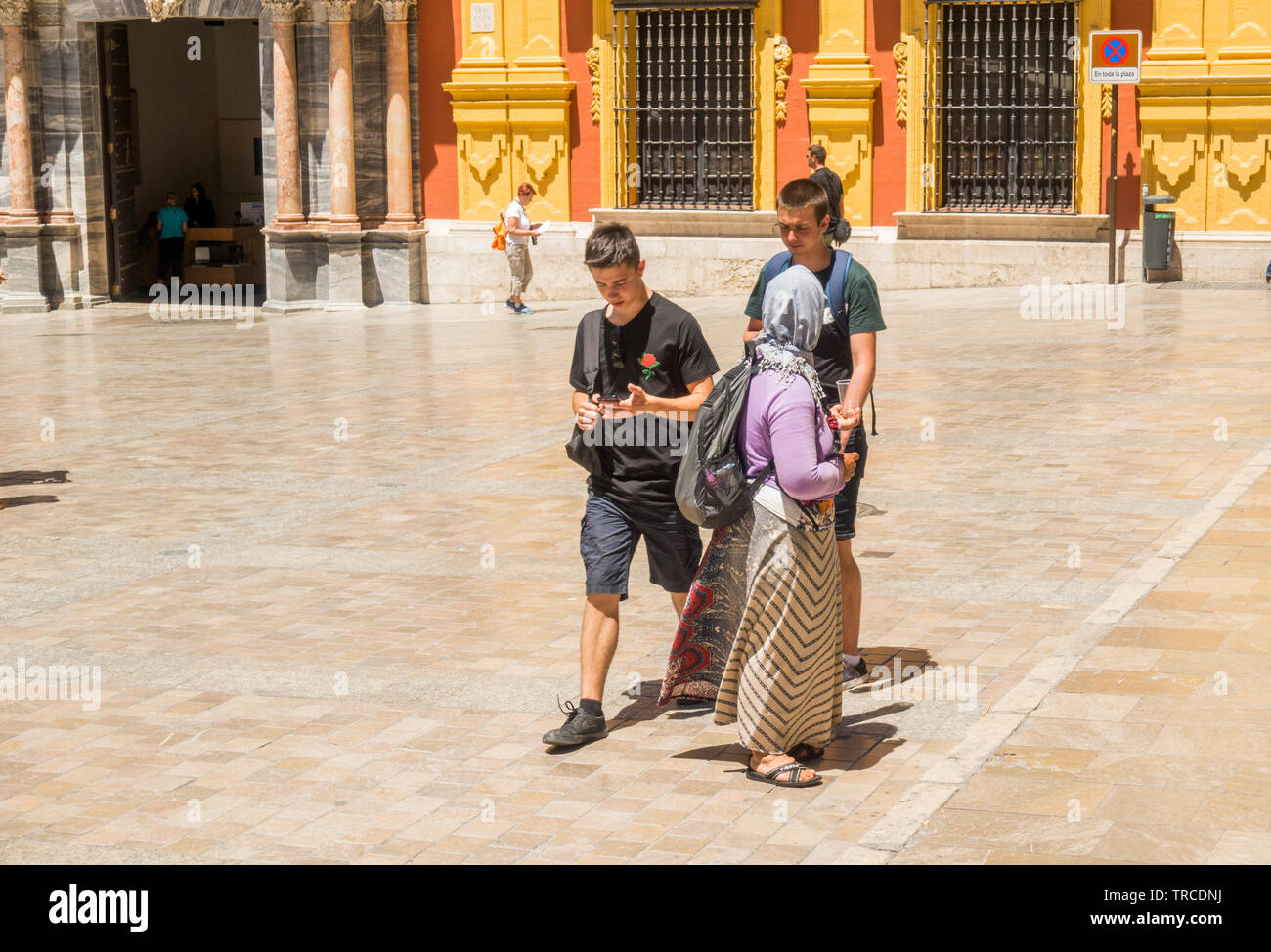 Les jeunes touristes passent par une femme mendiant dans les rues de Malaga, Andalousie, espagne. Banque D'Images