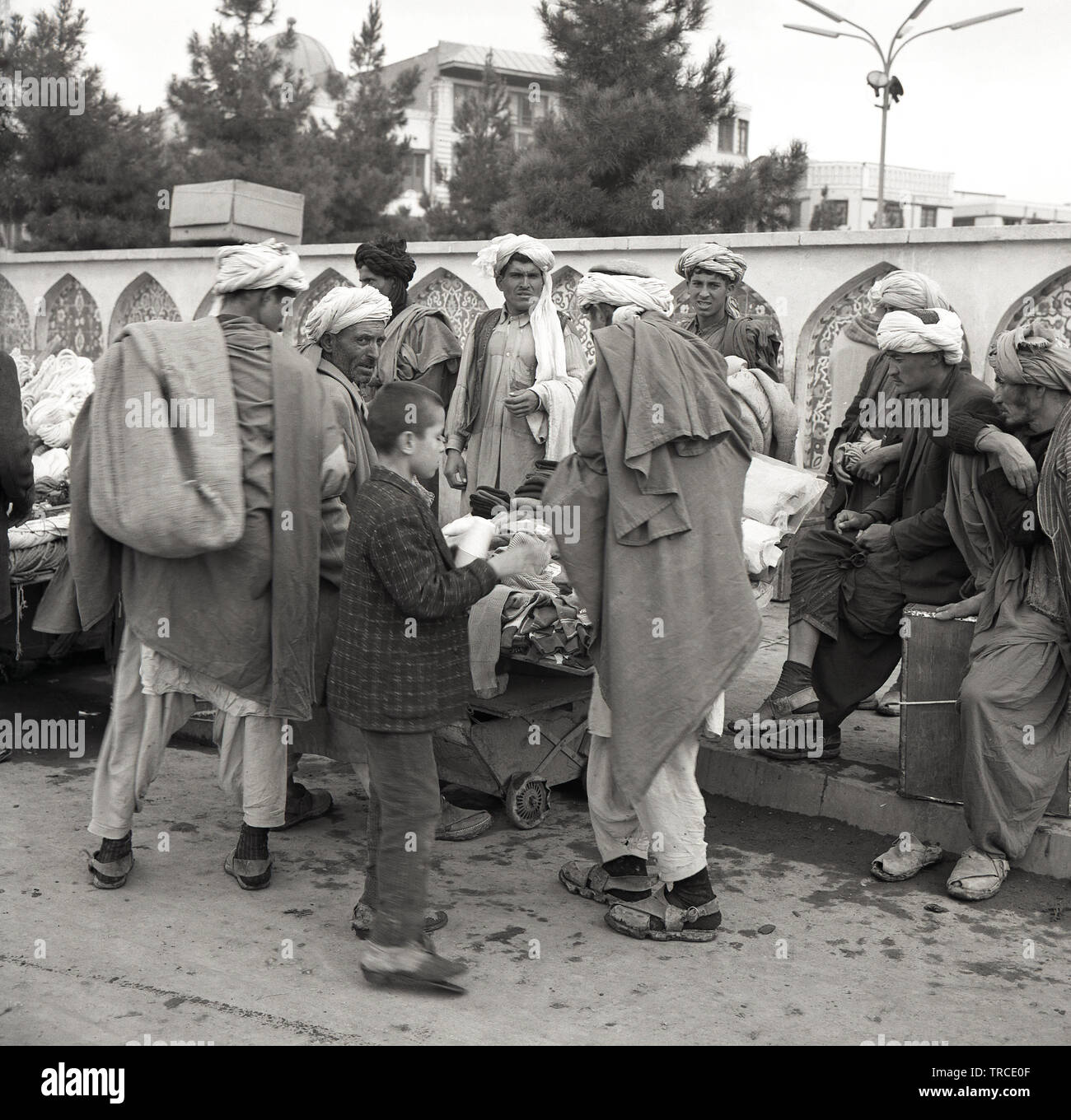 Années 1950, historiques, commerçants afghans portant des robes traditionnelles arabes et de casquettes, un Shemagh keffiyeh ou foulard ou afghan, se rassemblent à l'extérieur dans la rue en Afghanistan, Kabal. Banque D'Images