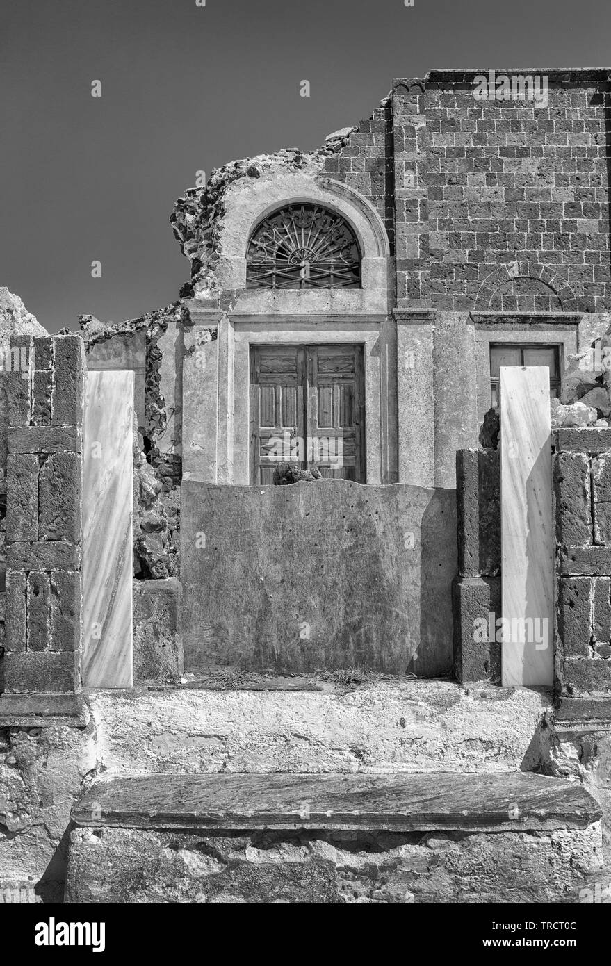 L'effritement des vestiges d'une porte patio de marbre montrant une porte en bois entourée d'un ancien bâtiment en brique derrière elle. Banque D'Images