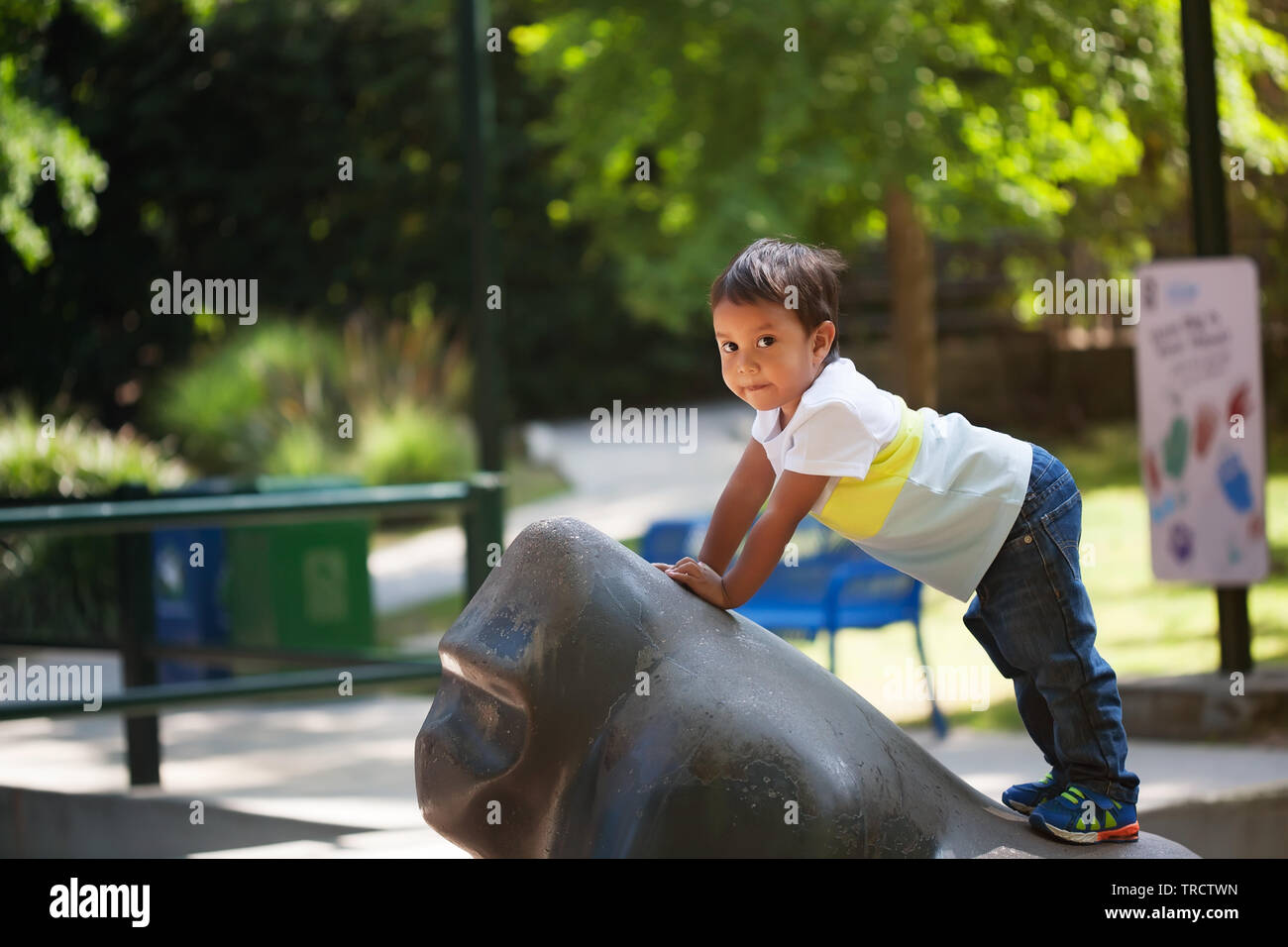 L'équilibrage de petit garçon lui-même sur une statue de singe à une aire de jeu pour les enfants qu'il a grimpé au coucher du soleil. Banque D'Images