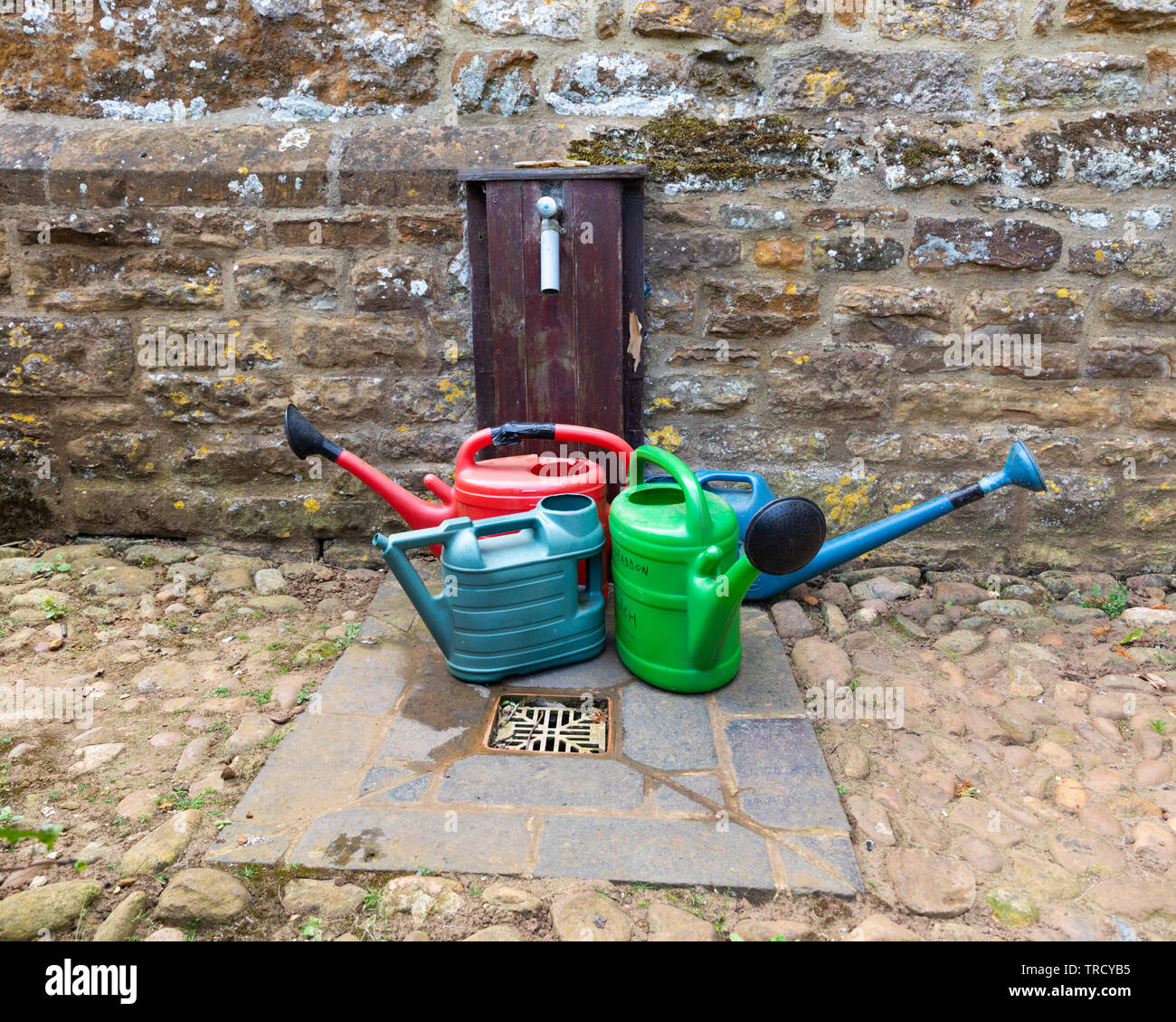 Cimetière de l'Ouest, le 11 avril 2004. Quatre couleurs, arrosoirs en plastique, avec leur bec vers l'extérieur, se tenir par un drain, sous un robinet. Banque D'Images