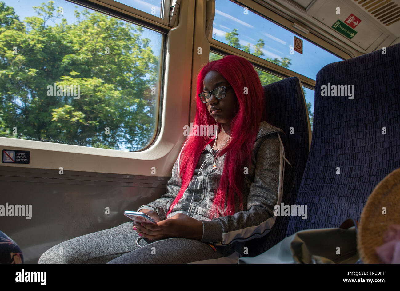 Jeune femme dans un train texting Banque D'Images