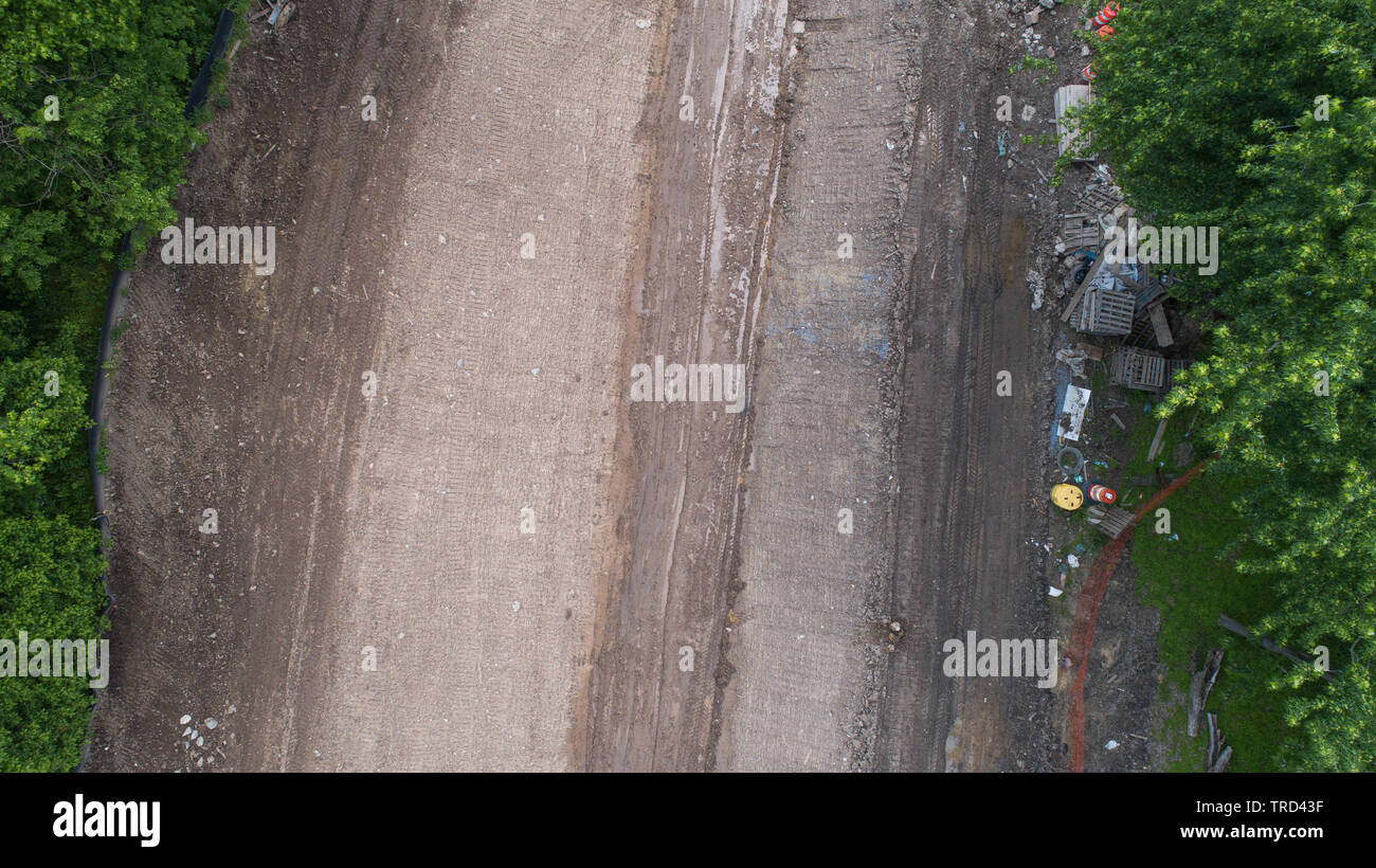 Drone aérien Photographie Vue de dessus directement sur la route de terre Chantier avec traces de débris et pile de détritus Arbres verts colorés Banque D'Images
