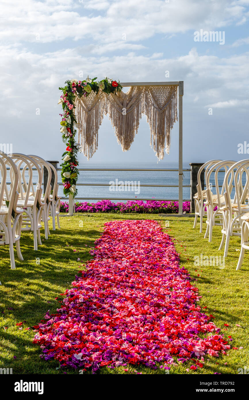 Arch dans mariage style Boho près de l'océan pour une cérémonie décoré de macrame et des fleurs fraîches, des chaises et de l'allée de pétales roses et rouges. Bali. Banque D'Images