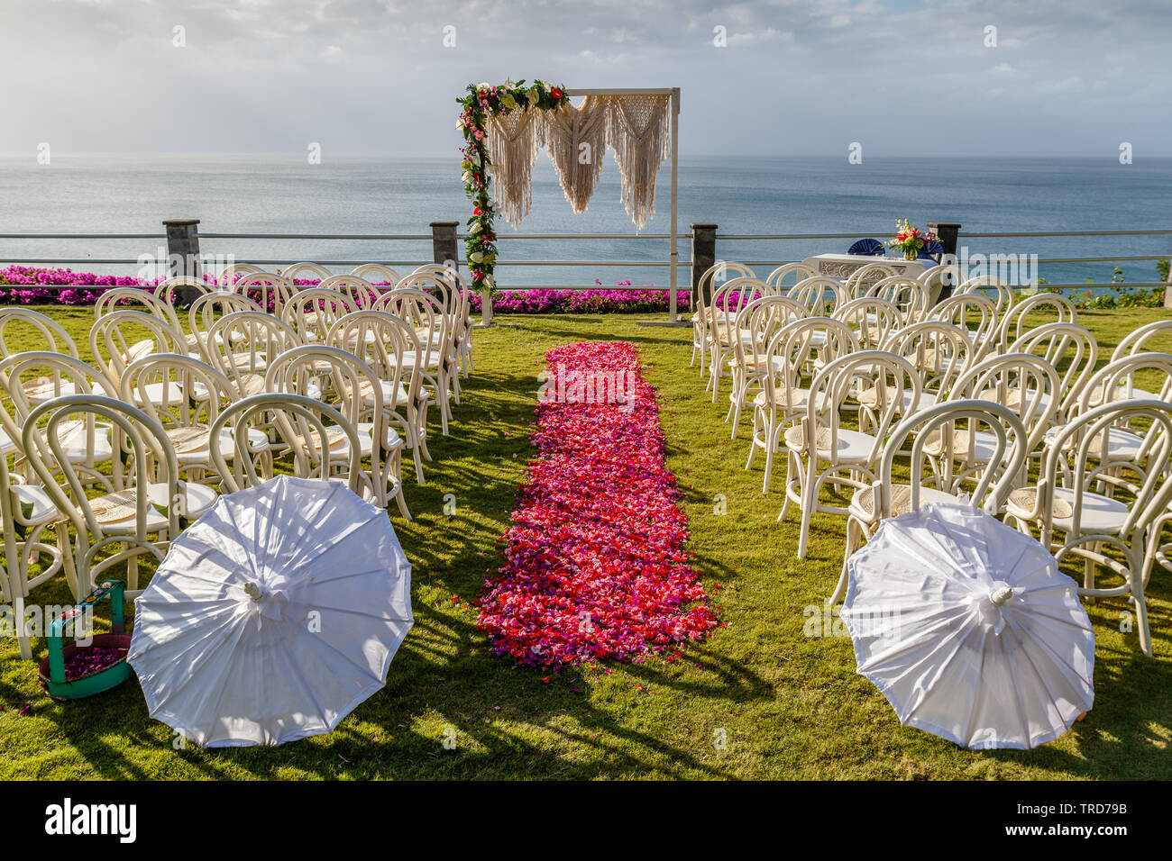Arch dans mariage style Boho près de l'océan de cérémonie décoré de macrame et fleurs fraîches. Chaises longues, parasols et l'allée de pétales roses et rouges. Bali Banque D'Images