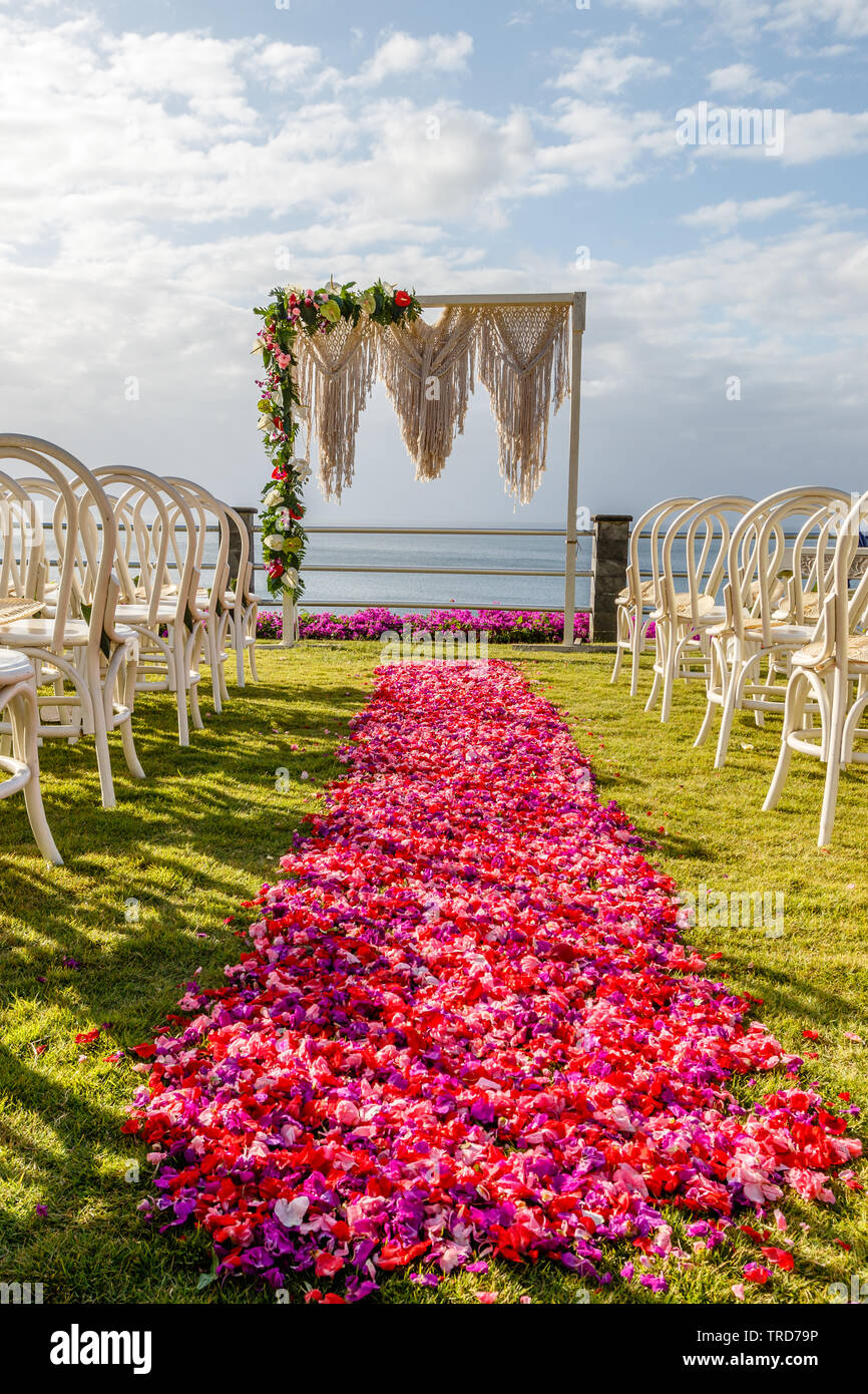 Arch dans mariage style Boho près de l'océan pour une cérémonie décoré de macrame et des fleurs fraîches, des chaises et de l'allée de pétales roses et rouges. Bali. Banque D'Images