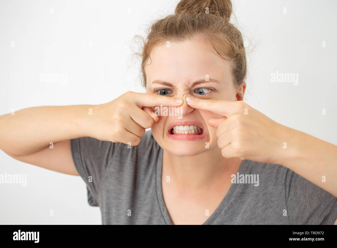 Young caucasian woman squeezing un bouton sur son nez, l'expression du visage drôle Banque D'Images