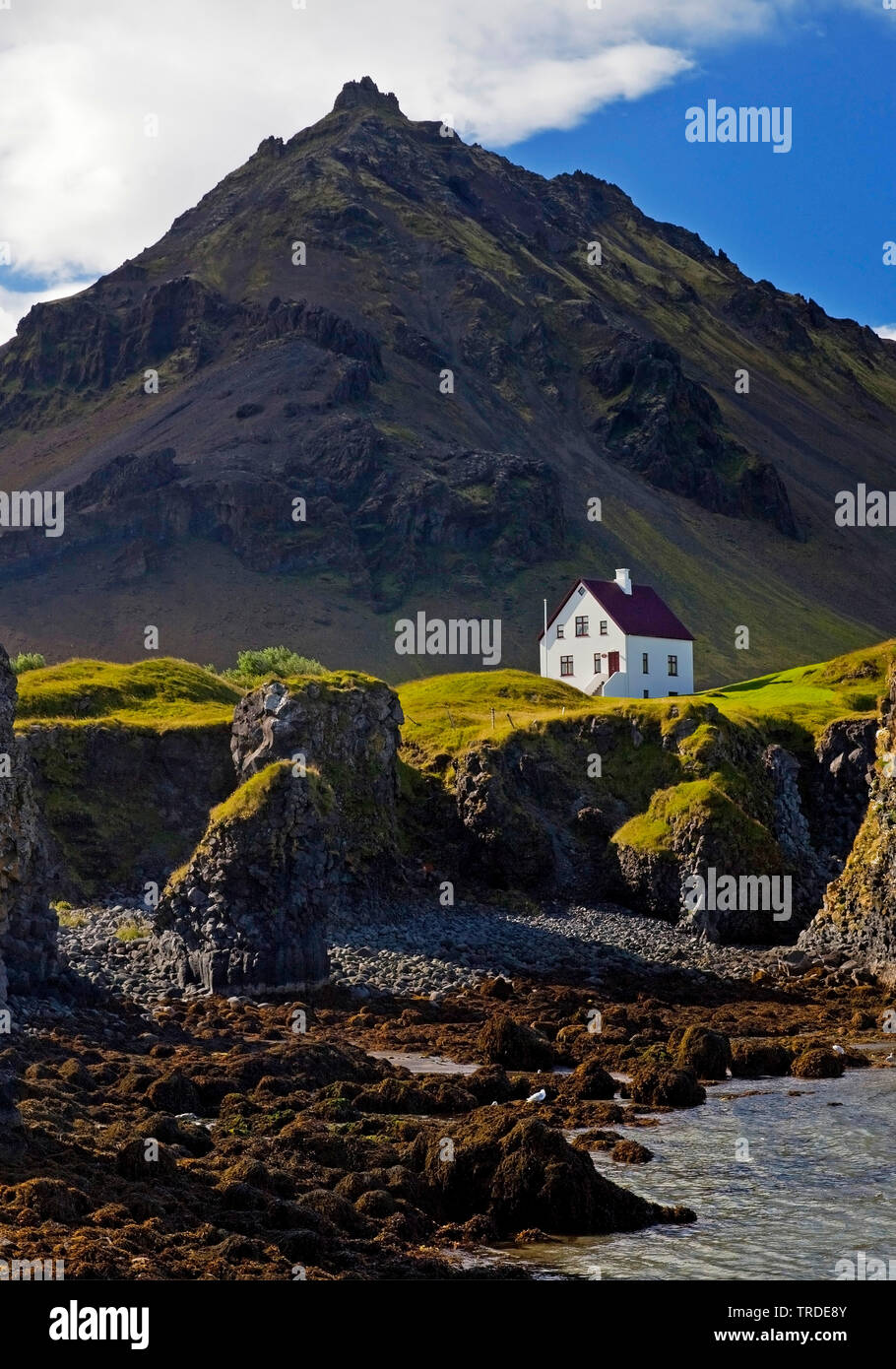 Maison sur la côte de basalte en face du volcan Stapafell, Islande, Vesturland, Arnarstapi, Snæfellsnes Banque D'Images
