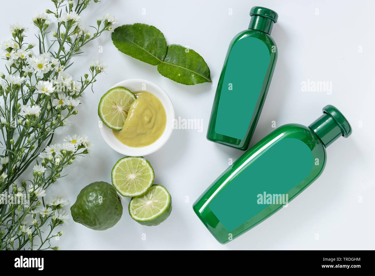 Produits naturels pour les cheveux concept. deux taille de bouteille en plastique vert avec étiquette vierge contiennent des plantes médicinales shampoing bergamote décorer avec les limes Banque D'Images