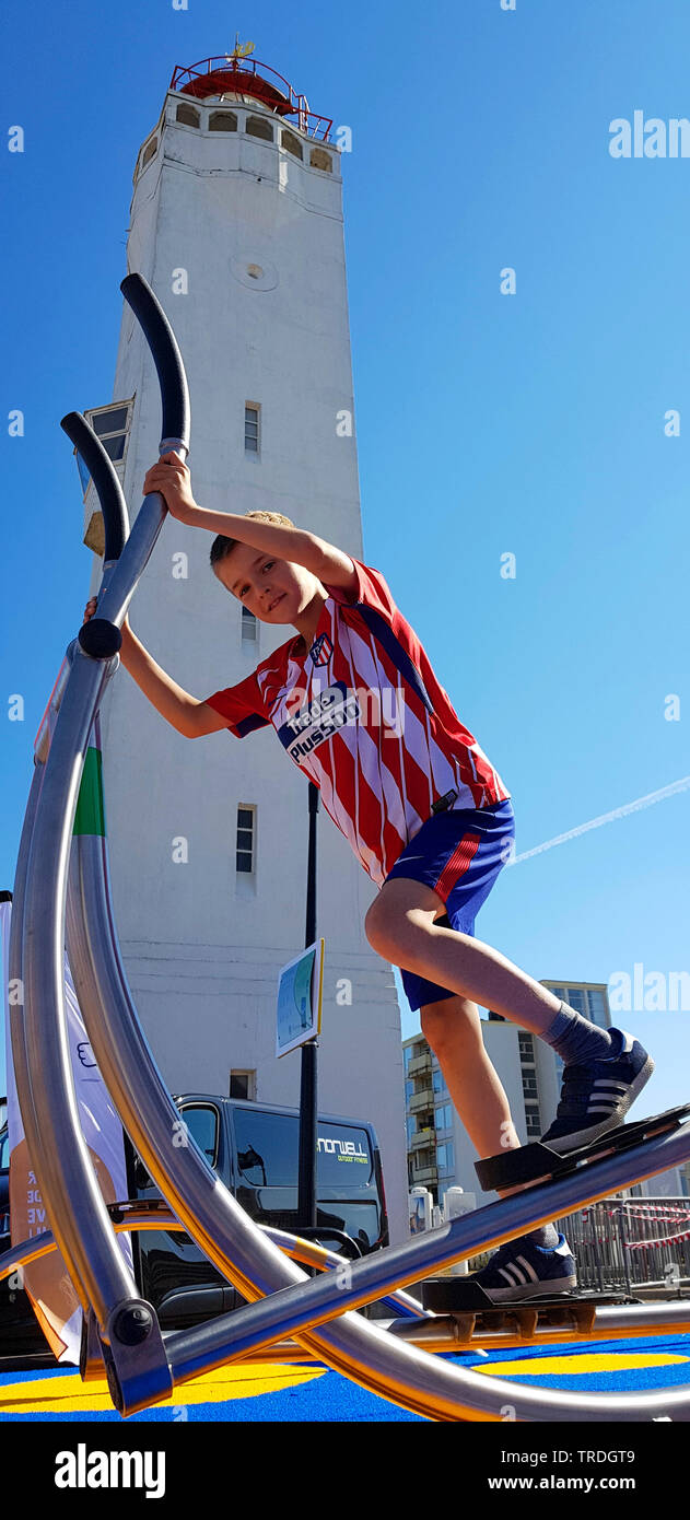 Garçon de la formation sur un cross trainer devant le phare de Noordwijk, Pays-Bas, Noordwijk aan Zee Banque D'Images