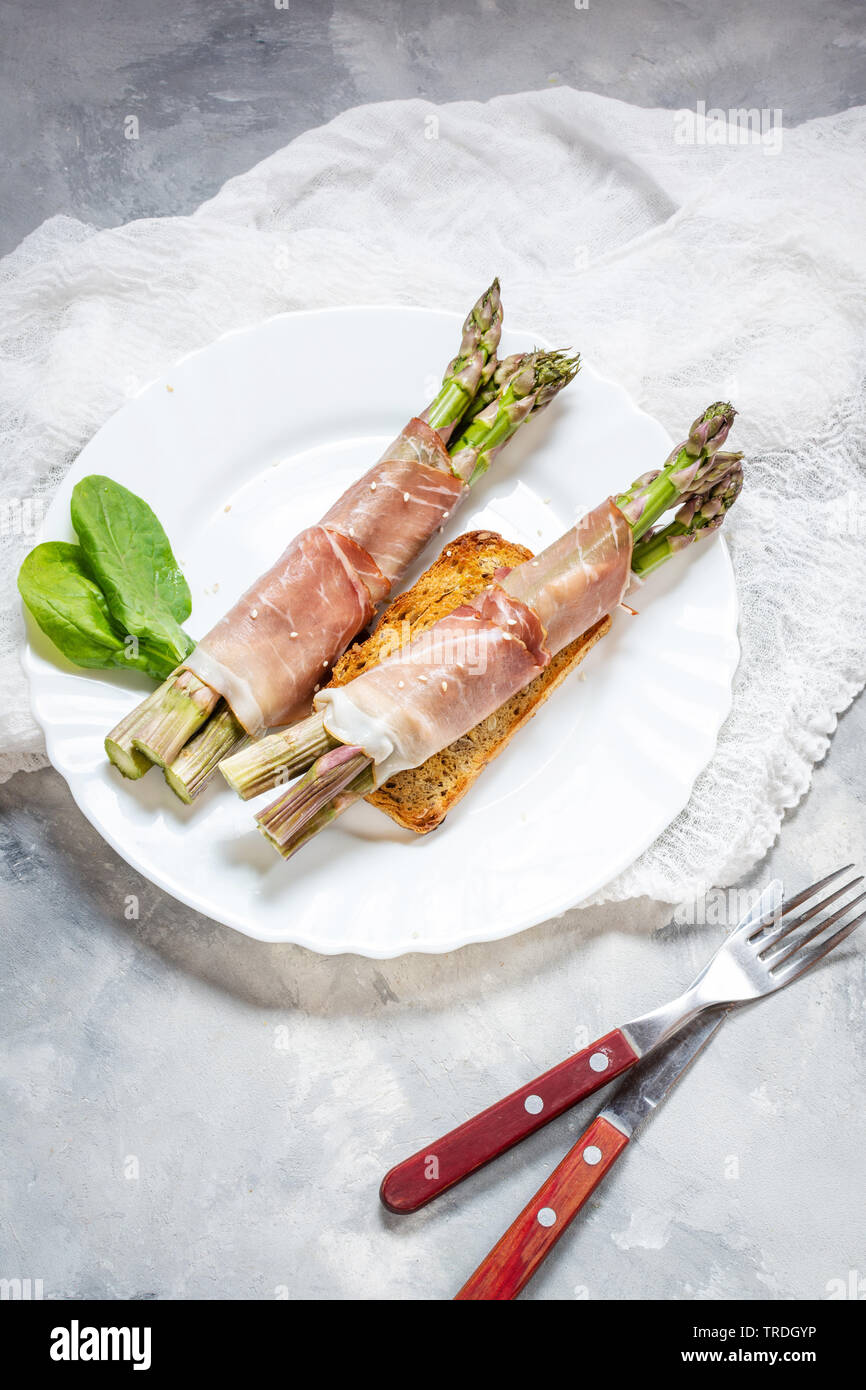 Jeunes frais enveloppé dans le Prosciutto Asperges viande sur une table béton rustique. Banque D'Images