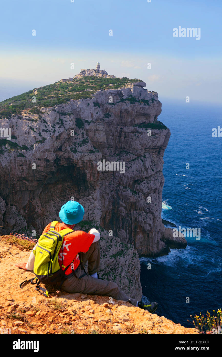 Wanderer assise sur le bord d'une speep face au phare de Capo Caccia , Italie, Sardaigne, Alghero Banque D'Images
