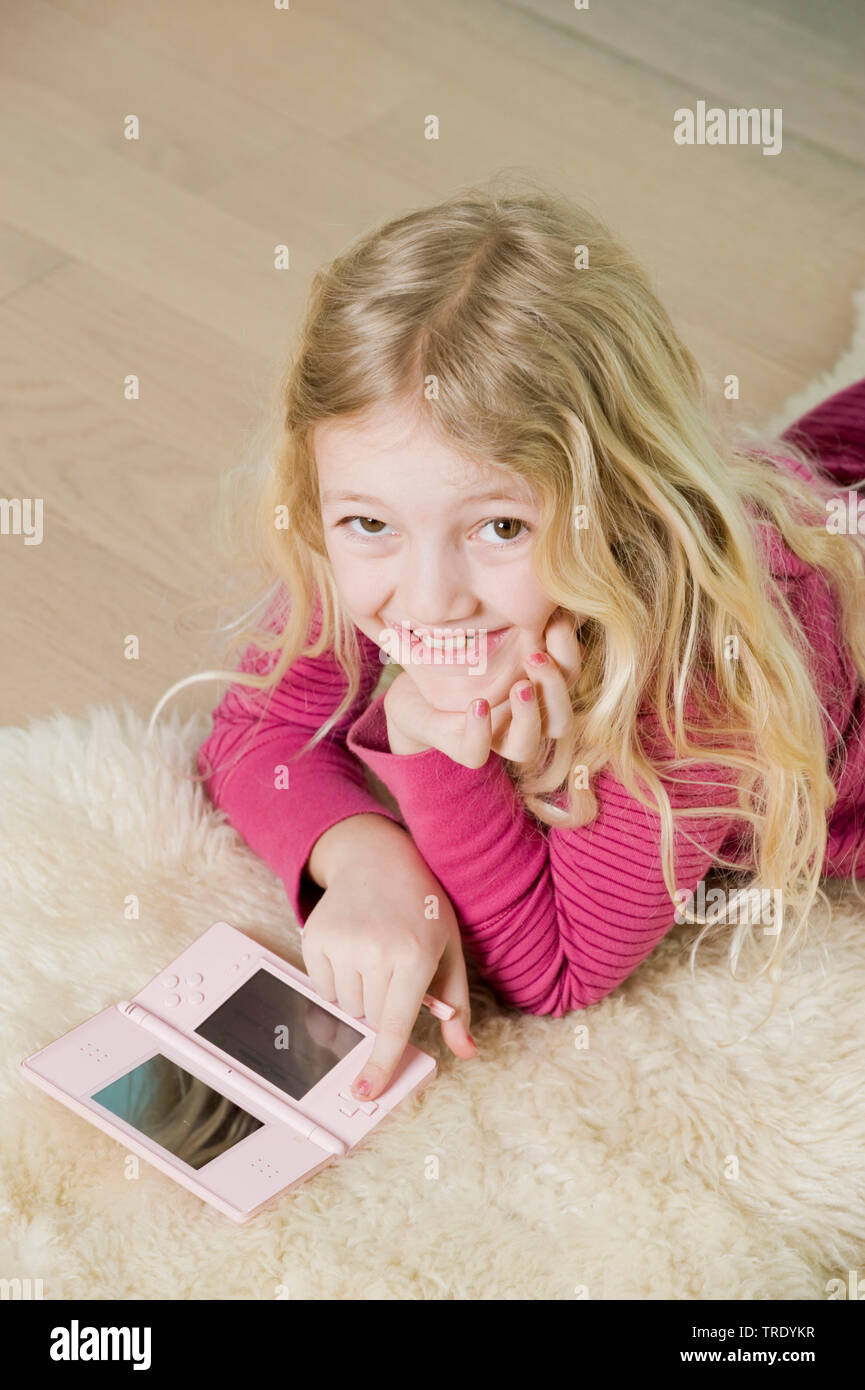 Portrait d'une fille allongée sur le sol et jouer avec sa console de Nintendo Banque D'Images Portrait d'une fille allongée sur le sol et jouer avec sa console de Nintendo Banque D'Images