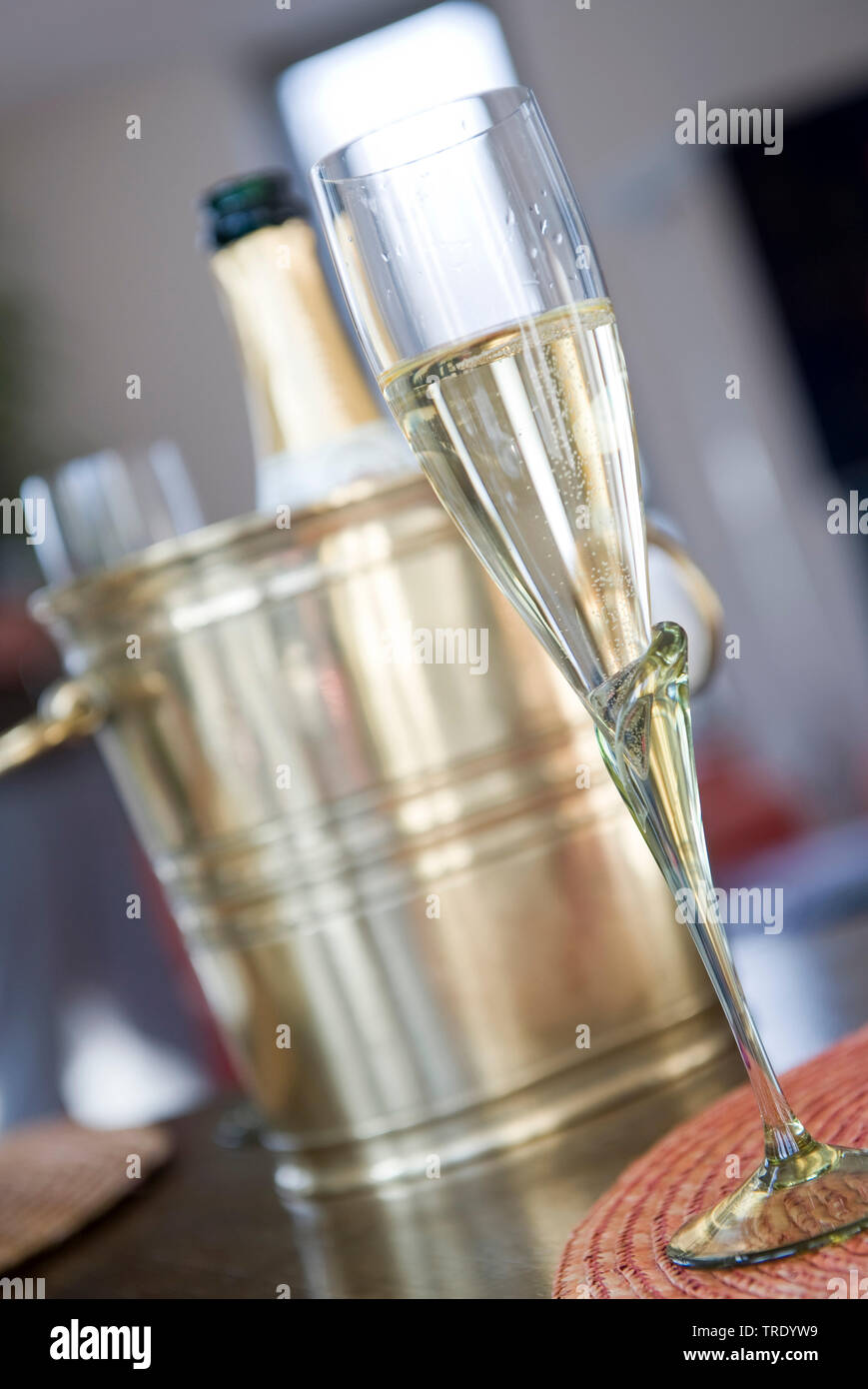 Verre à moitié plein champagner devant une bouteille de champagne dans un refroidisseur de bouteille Banque D'Images