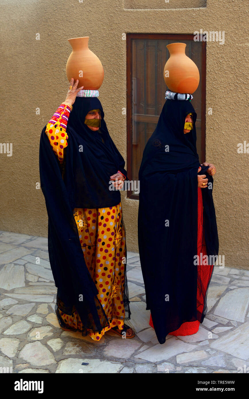 L'équilibrage des femmes voilées à l'argile sur la tête, Emirats Arabes Unis, Dubai Banque D'Images