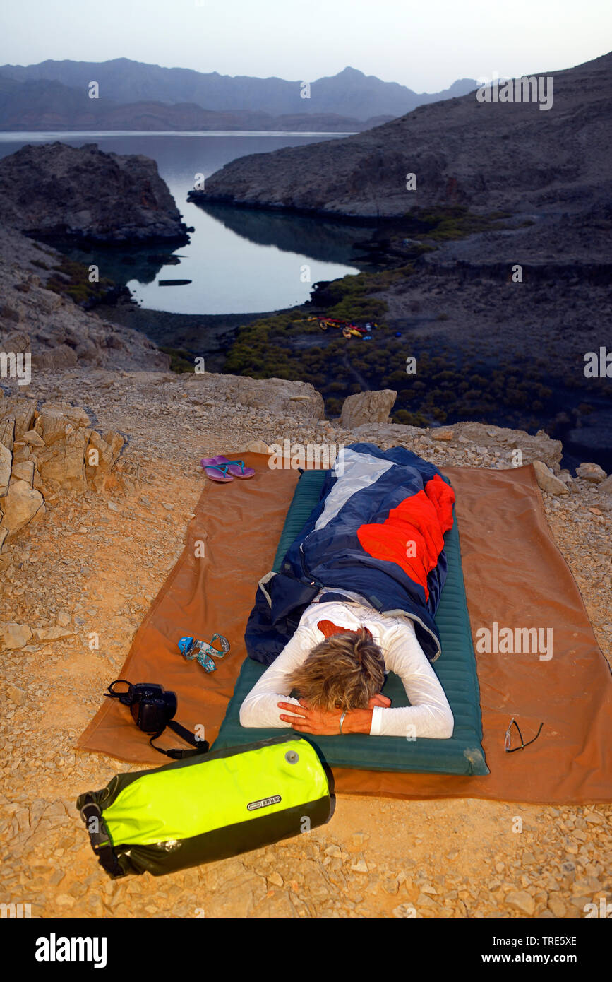 Femme passer la nuit en plein air sur la côte rocheuse du détroit d'Ormuz, Oman, Shamamar, Khasab Banque D'Images