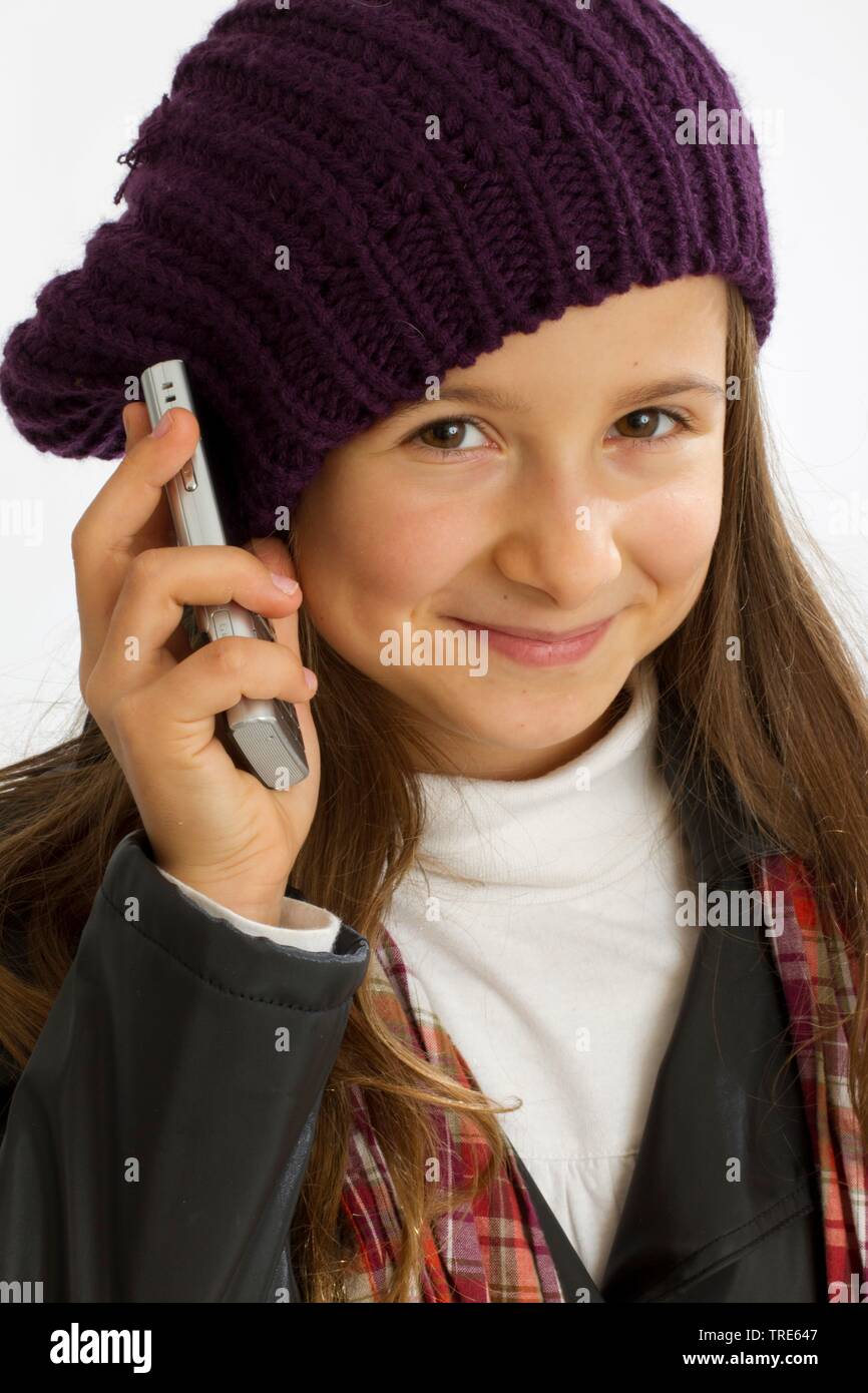 Portrait d'une jeune fille aimable holding a mobile à son oreille et souriant dans l'appareil photo Banque D'Images