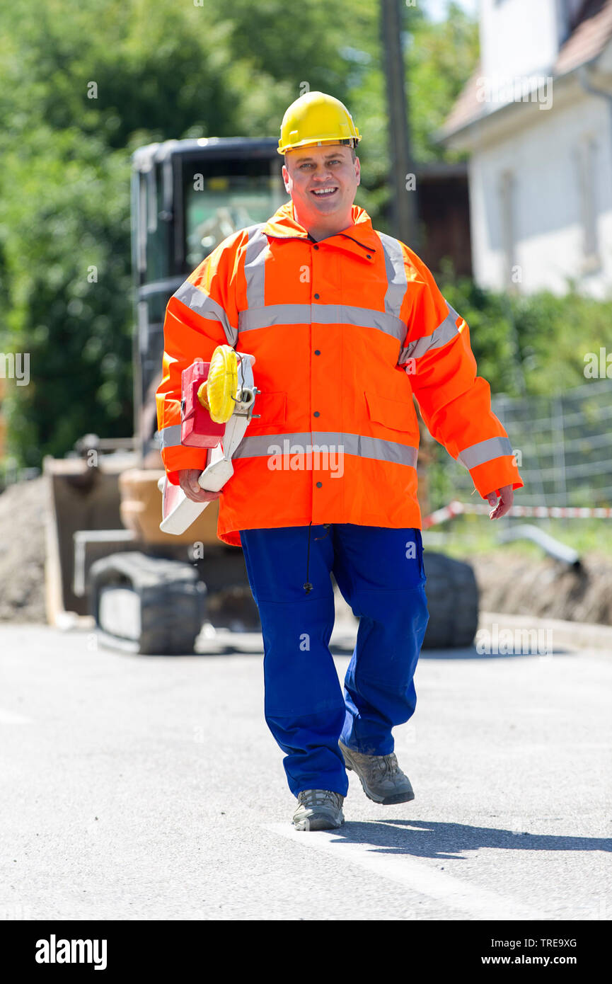 Travailleur de la construction d'une veste haute visibilité orange, faisant parties d'un barrage routier avec la construction de détresse Banque D'Images