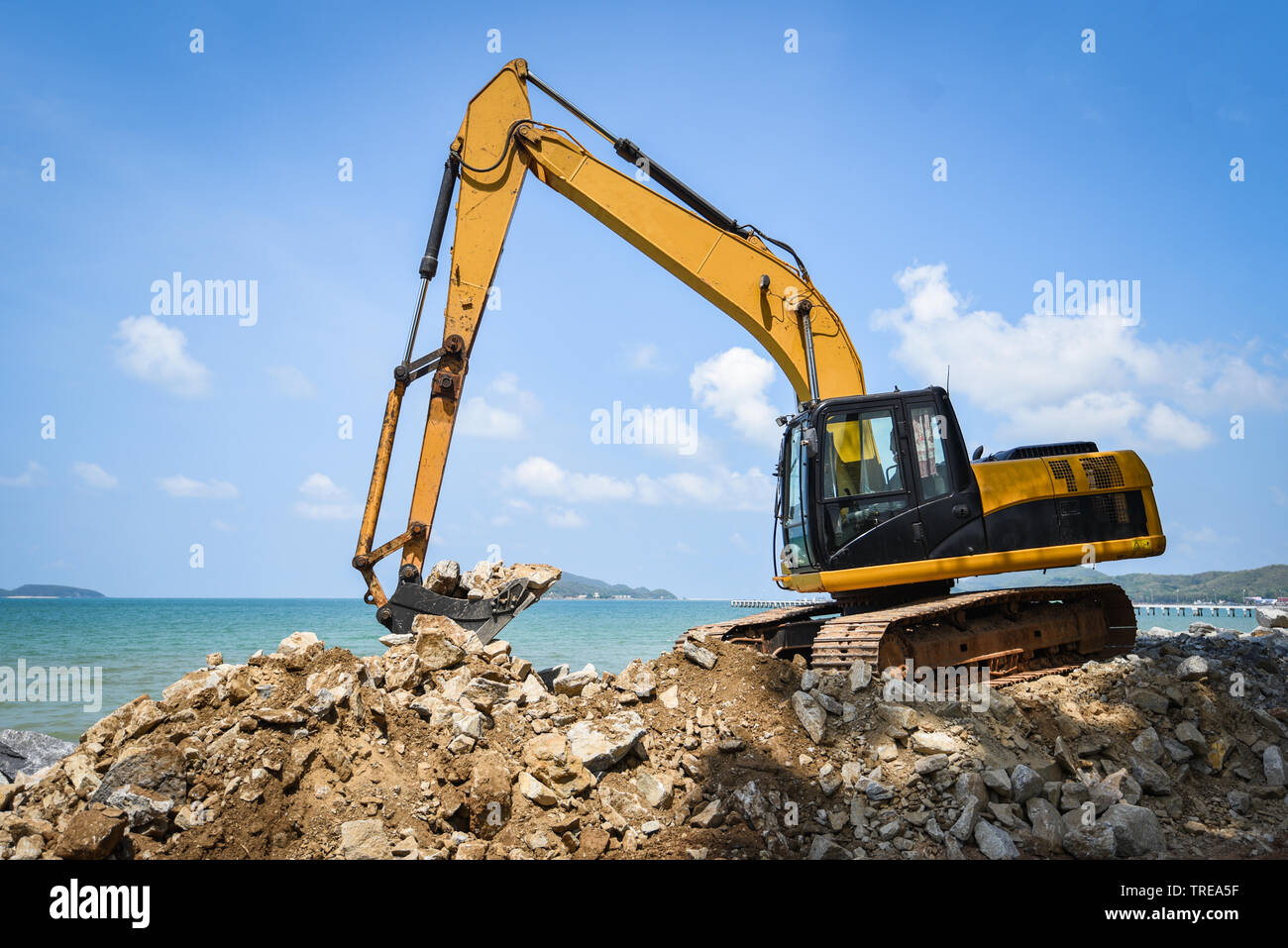 Digger excavator chargeuses pelleteuses de chantier de construction en  pierre sur la plage mer océan et fond de ciel bleu Photo Stock - Alamy