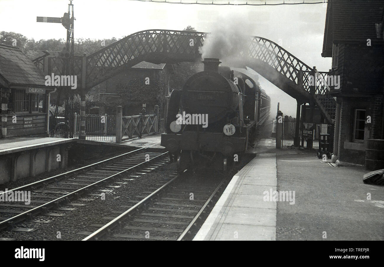 1950, historique, un train à vapeur entrant dans la gare, du village de Chiworth, près de Guildford, Surrey, Angleterre, ROYAUME-UNI. Le numéro à l'avant de la locomotive à vapeur du chemin de fer britannique est 31796. La gare a commencé ses activités en 1849 et était à l'origine connue sous le nom de Chilworth et Albury, incorporant le village voisin d'Albury. À ce moment-là, la vieille passerelle historique et les portes de passage étaient toujours en service. Banque D'Images