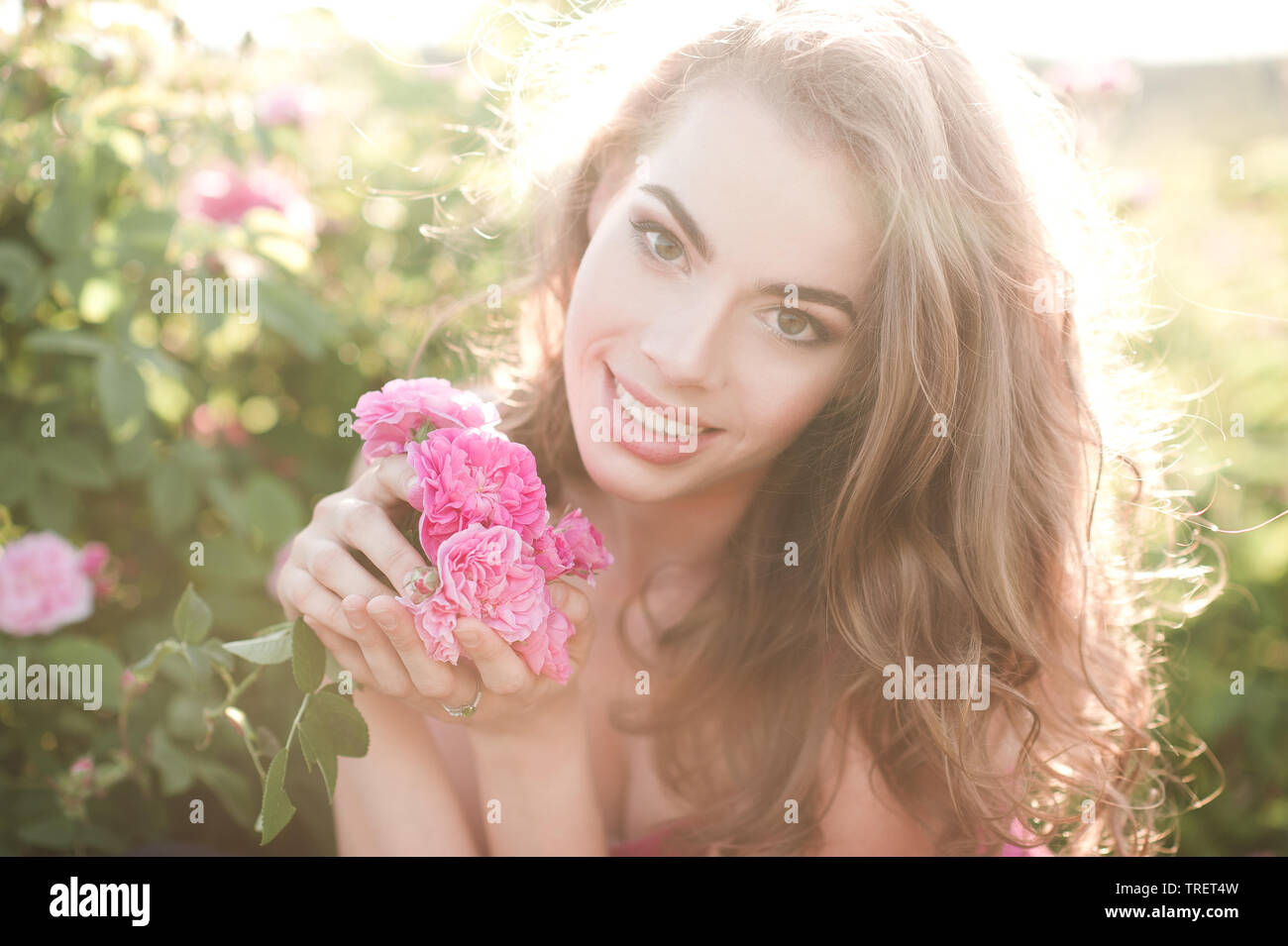 Smiling beautiful blonde woman holding 24-29 ans fleur posant dans le pré à l'extérieur. En regardant la caméra. L'heure d'été. Banque D'Images
