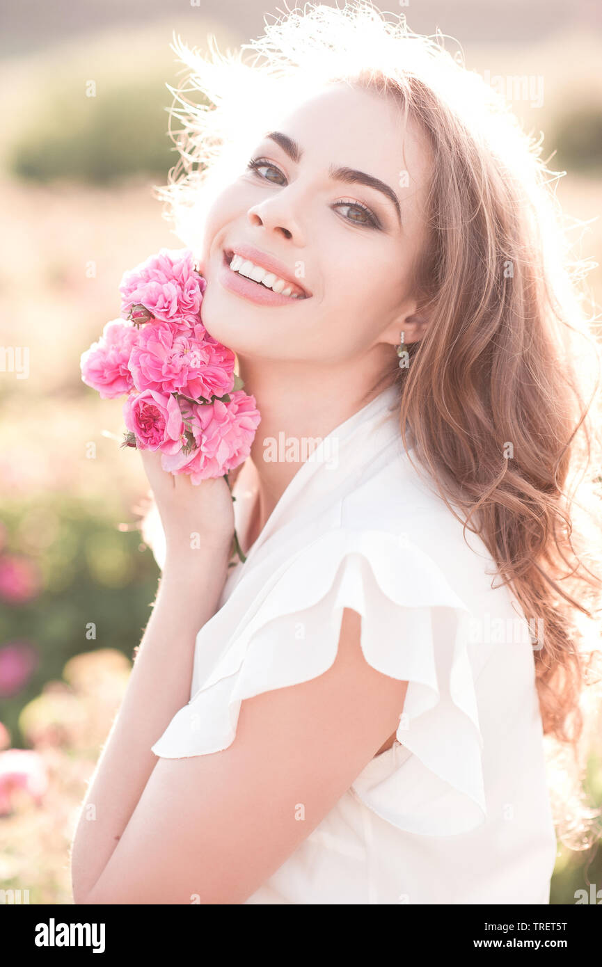 Smiling blonde girl à 29 ans à l'extérieur. roses holding En regardant la caméra. 20s. La saison d'été. Banque D'Images
