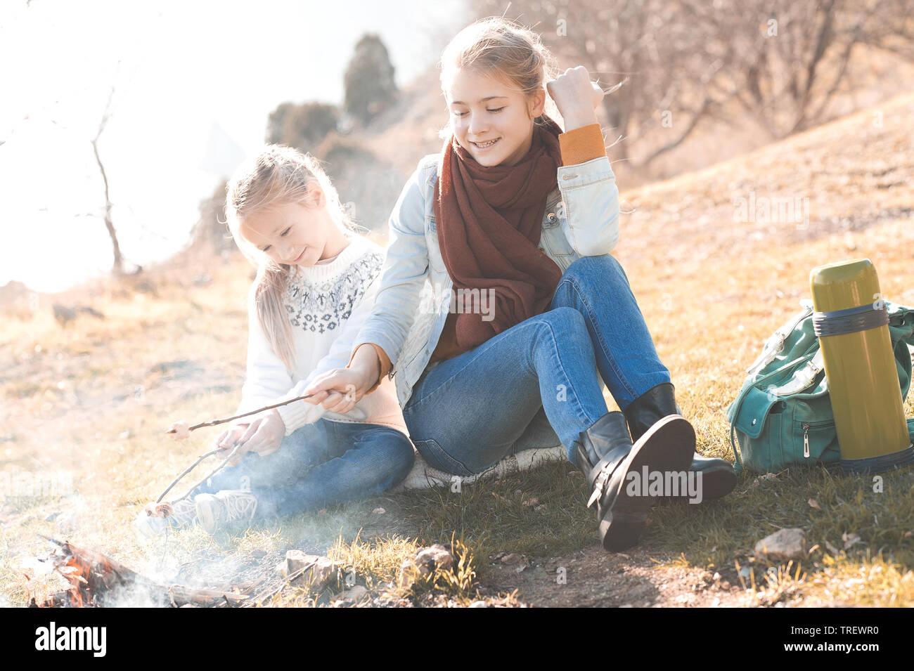 Deux filles en guimauve de brunissage pour enfants à l'extérieur du feu. L'enfance. Banque D'Images