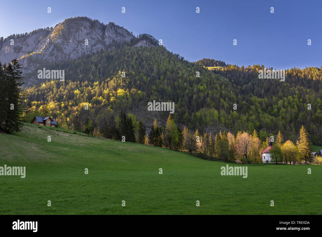 Coucher du soleil calme dans la région de Logarska Dolina, la Slovénie. Dans la vallée du soleil chaud, fin. Chapelle en rotonde et ferme sur des pentes de collines alpines dans l'ombre. Derniers rayons Banque D'Images