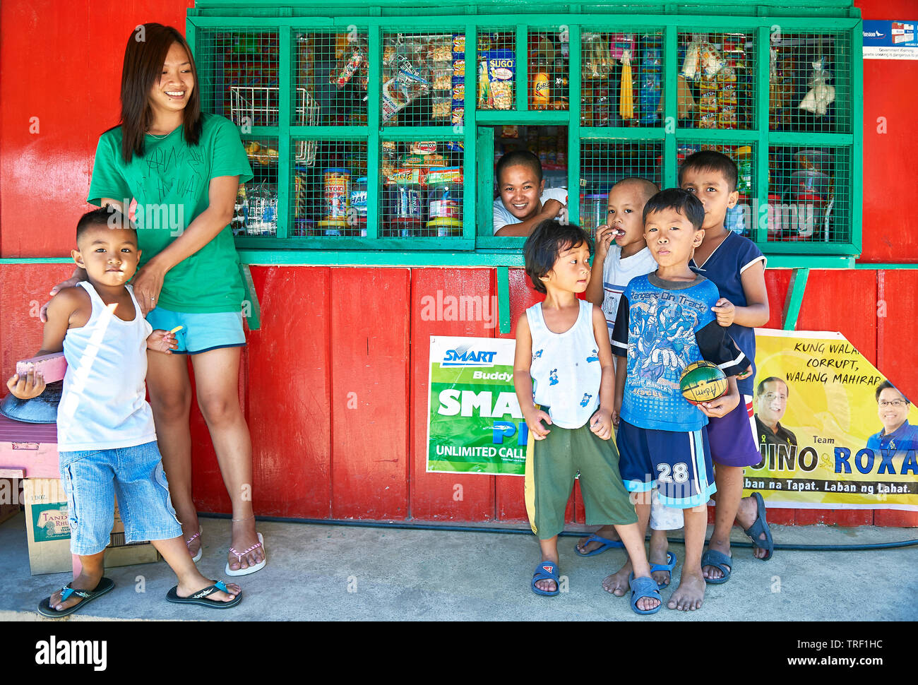 Puerto Princesa City, Palawan, Philippines : un groupe de jeunes garçons et une mère debout devant un magasin de sari-sari coloré Banque D'Images