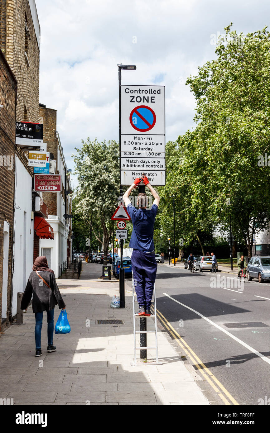 Un travailleur du conseil d'al adder modification d'un match du jour l'avis de restriction de stationnement à Islington, Londres, Royaume-Uni Banque D'Images