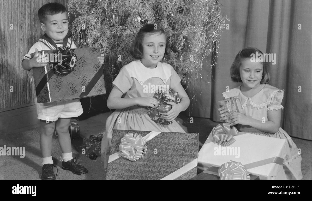 Années 1950, historiques, children avec présente à Noël par l'arbre de Noël, USA. Banque D'Images