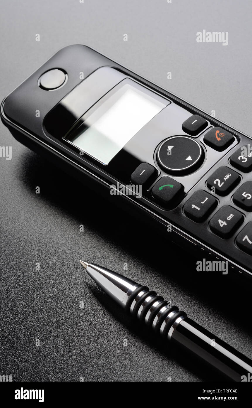 Téléphone et stylo à bille sur la surface grainé noir Banque D'Images
