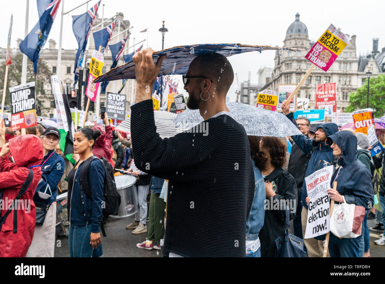 4 juin 2019. Londres, Royaume-Uni. Trump anti rassemblement à Westminster. Un protestataire se cache de la pluie sous la plaque. Banque D'Images