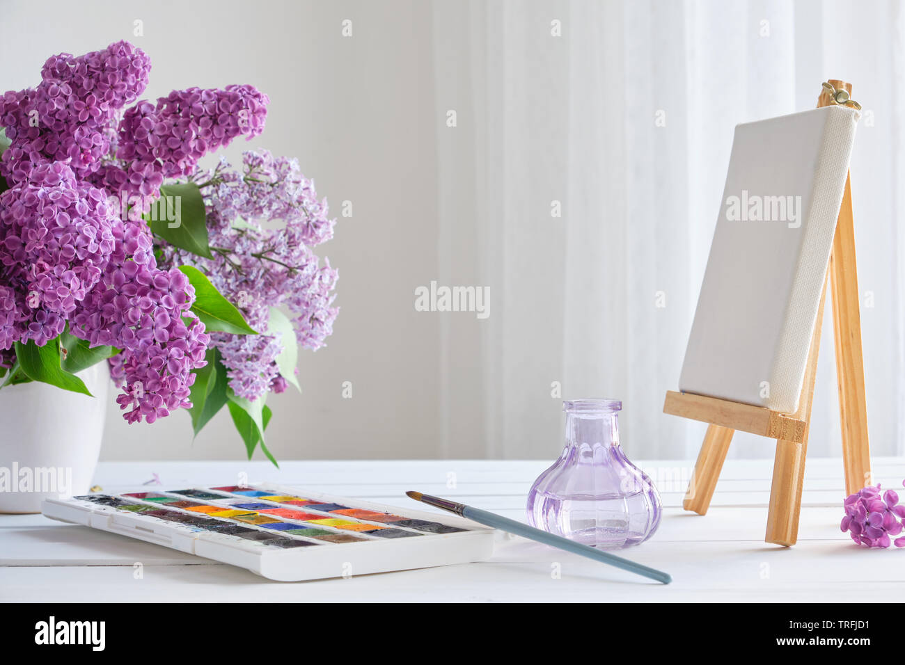 Les peintures, aquarelle sur toile et chevalet fleurs lilas blanc bouquet sur table. Banque D'Images