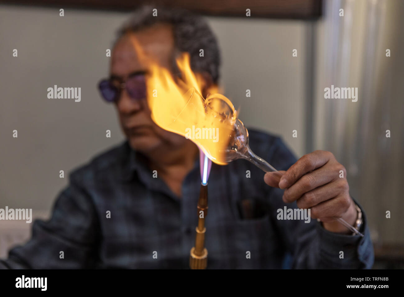 Macro Close up de souffleur de verre travailler avec flamme sur un verre de  vin à la main à partir du précieux cristal dans un atelier. Concept de  haute qualité, faits à
