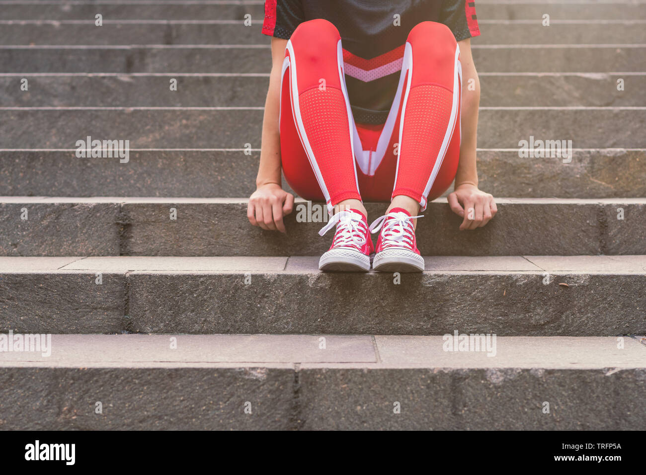 Femme assise sur les escaliers, elle porte des vêtements tout Banque D'Images