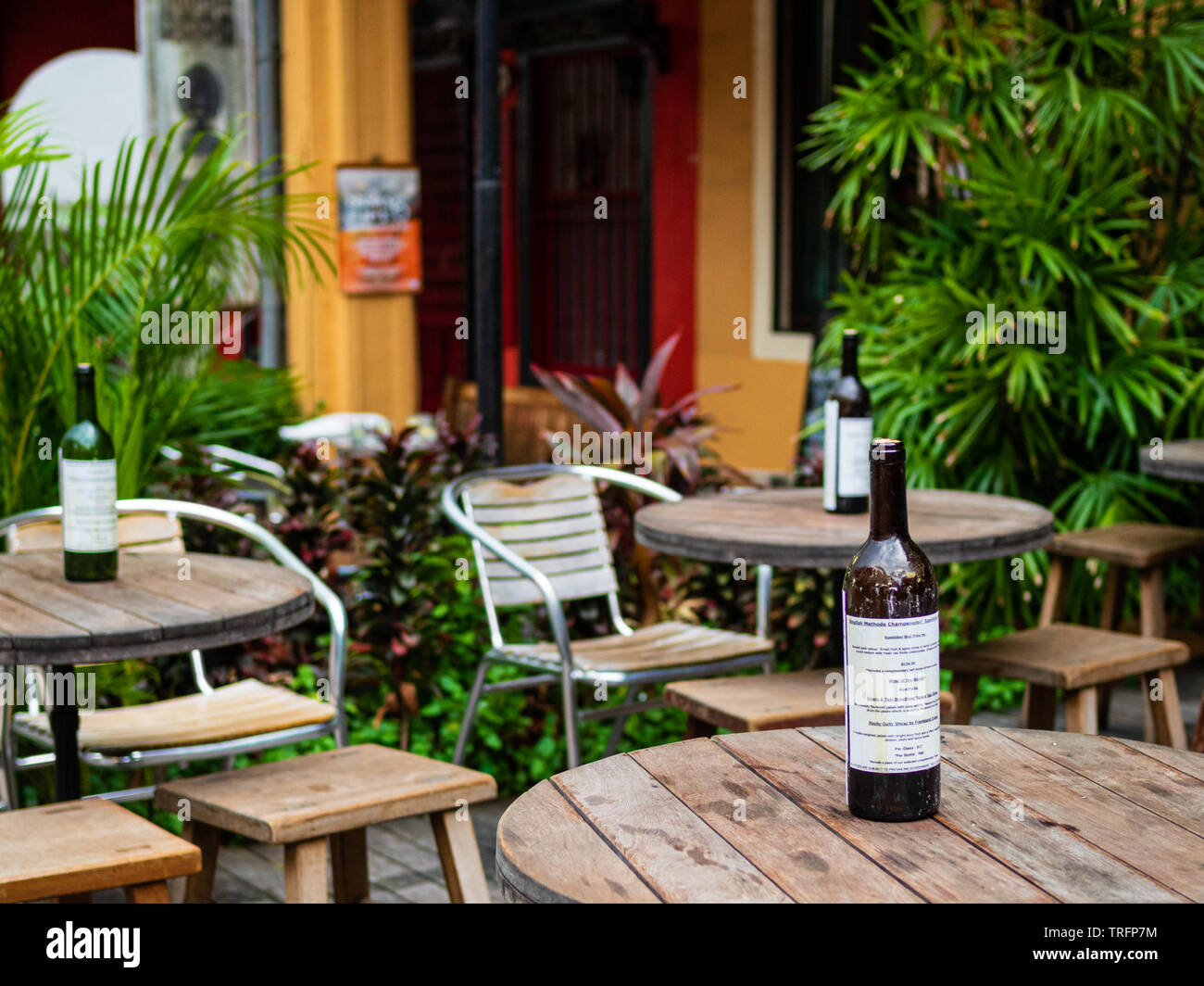 Un dîner décontracté en plein air cafe de l'ouest avec un mobilier rustique en bois, des plantes et des bouteilles de vin. Banque D'Images