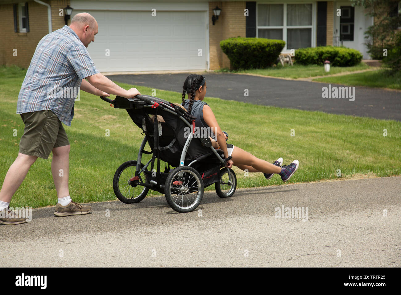 L Age Moyen D Un Homme Pousse Un Adolescent Dans Une Poussette A Travers Un Lawrence Quartier De L Indiana Photo Stock Alamy