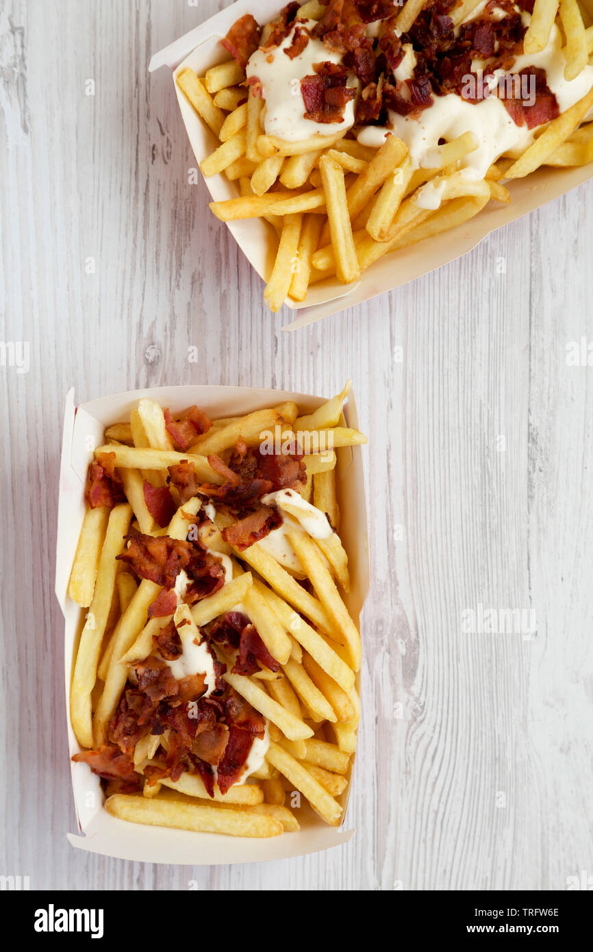 Vue de dessus, frites avec sauce au fromage et bacon dans des boîtes de carton. Mise à plat, à partir de ci-dessus, les frais généraux. Banque D'Images