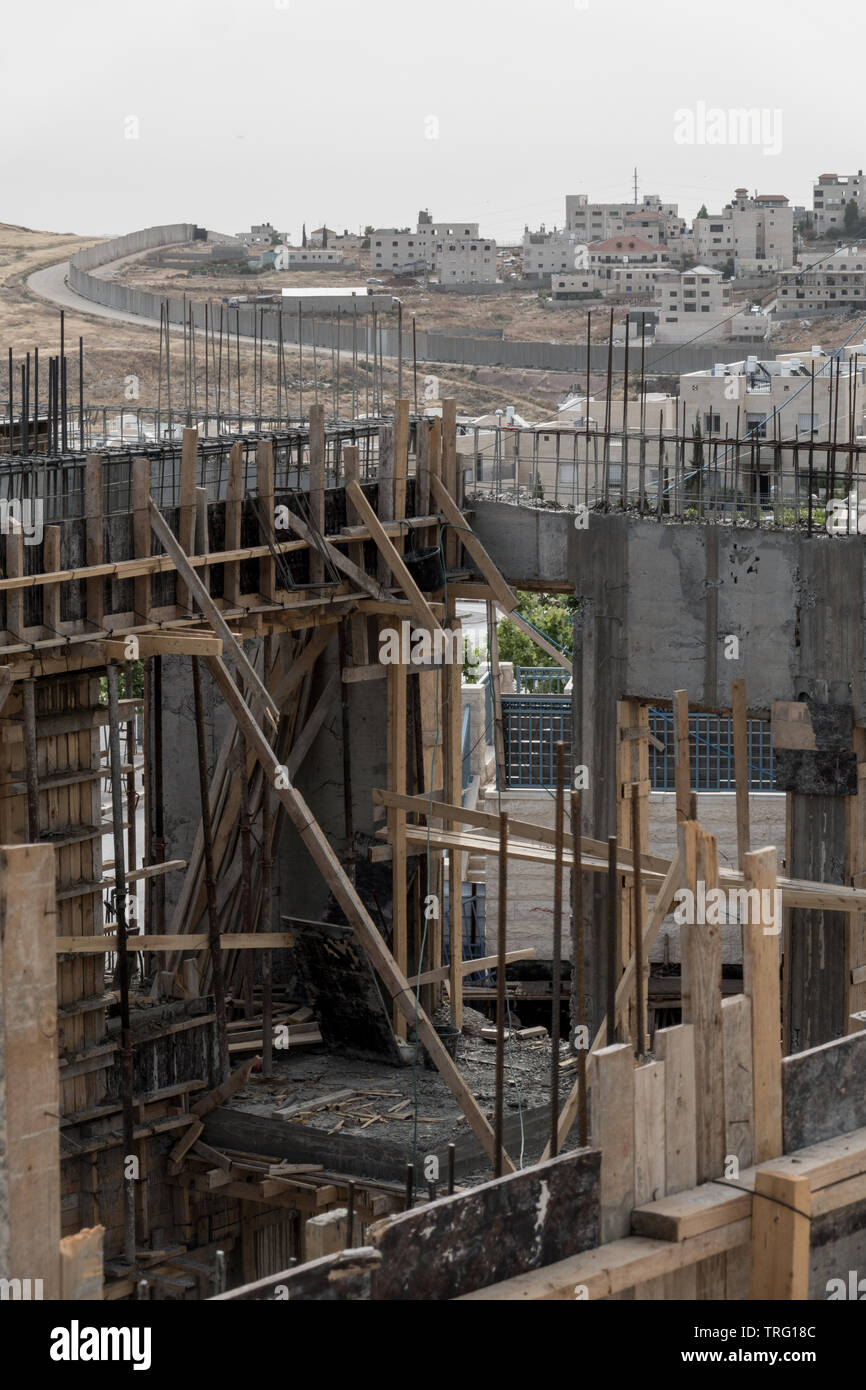 Jérusalem, Israël. 5 juin, 2019. Une vue vers l'Est de Jérusalem, Pisgat Zeev illustre quartier construction en cours au premier plan, avec la barrière de sécurité d'enroulement au milieu de terrain et une ville palestinienne au-delà. Ministère du logement d'Israël a récemment publié des appels d'offres pour la construction de 805 nouveaux logements dans le quartier de Ramot et Pisgat Zeev condamnation de l'UE de dessin (01 juin 2019) et a déclaré "l'Union européenne est fermement opposé à la politique de colonisation d'Israël, y compris à Jérusalem-Est, ce qui est illégal en vertu du droit international et un obstacle à la paix" et davantage de forme UK's Banque D'Images