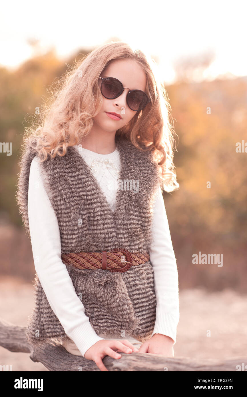 Teen girl elegante 14 16 ans gilet fourrure et des lunettes de soleil en plein air au cours de l automne les arbres. Looking at camera.l enfance Photo Stock Alamy